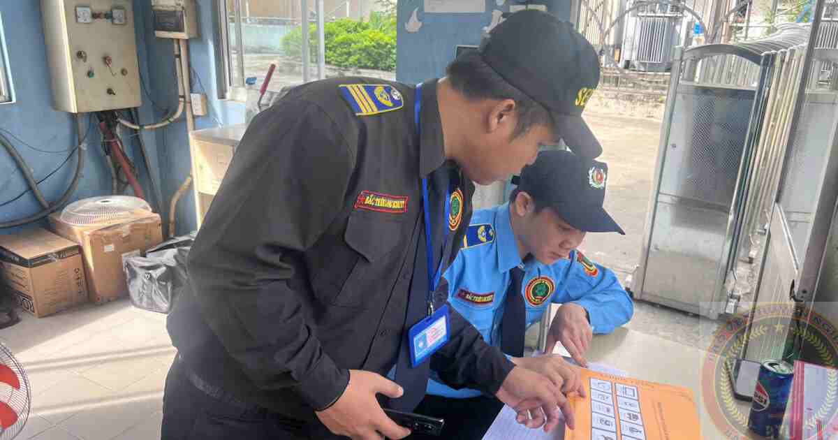 Nhân viên bảo vệ văn phòng kiểm tra sổ trực và bàn giao nhiệm vụ